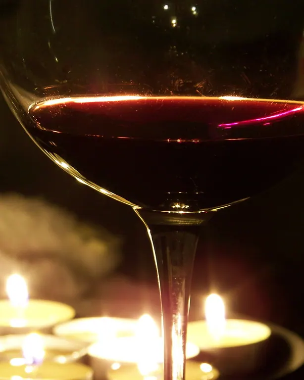 Copa de vino tinto servida a la luz de las velas